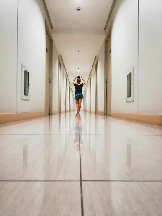 woman in a blue dress is walking down a hall