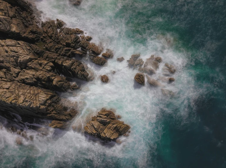 some rocks and water with foamy blue water