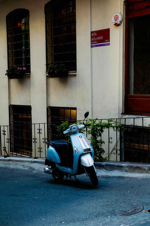 a blue and white scooter parked next to a tall building