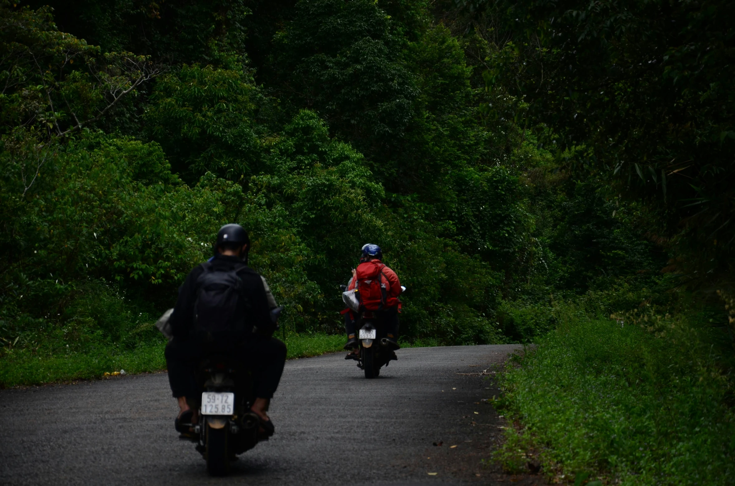 a pair of motorcyclists traveling down the road