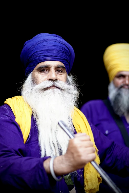 two bearded man wearing turbans and holding a umbrella