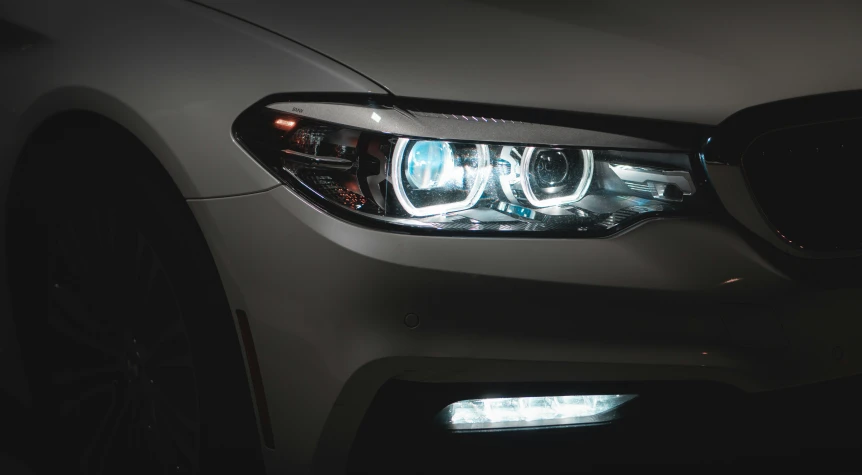 the headlights on a white bmw car lit by headlights