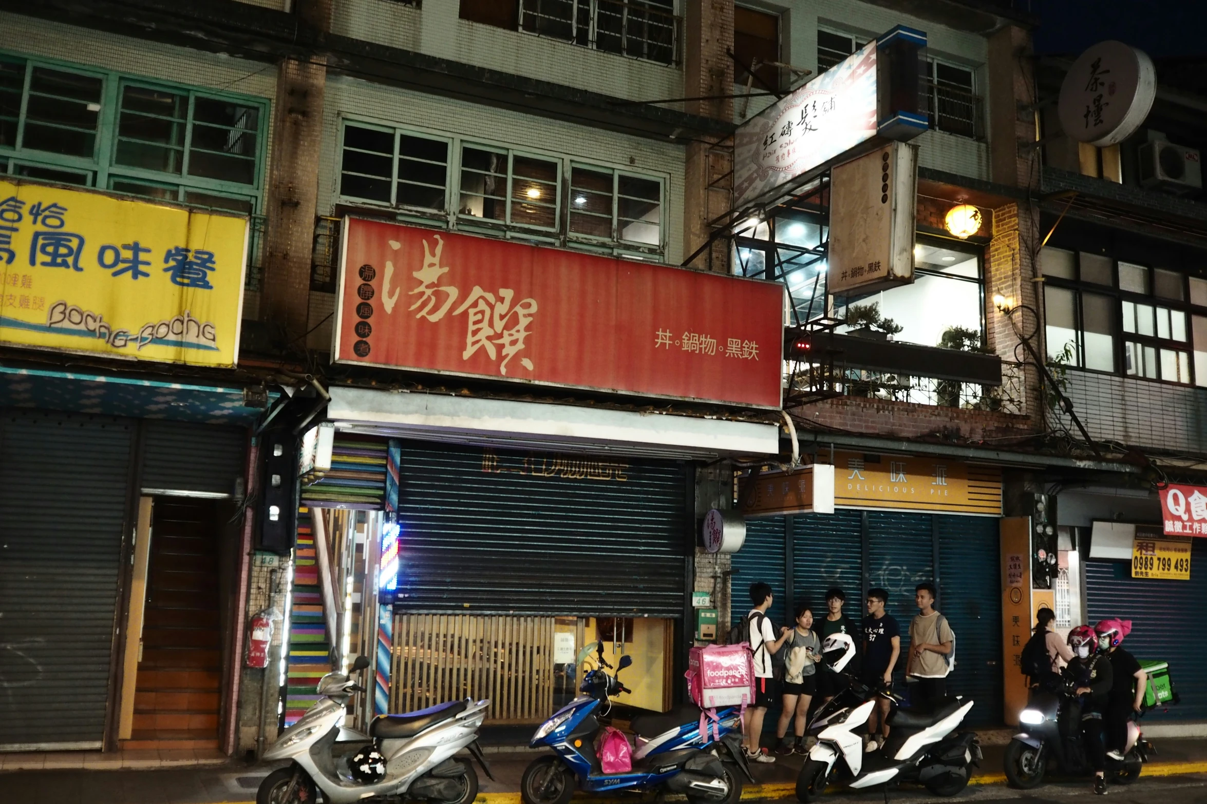 people stand outside of an asian building at night