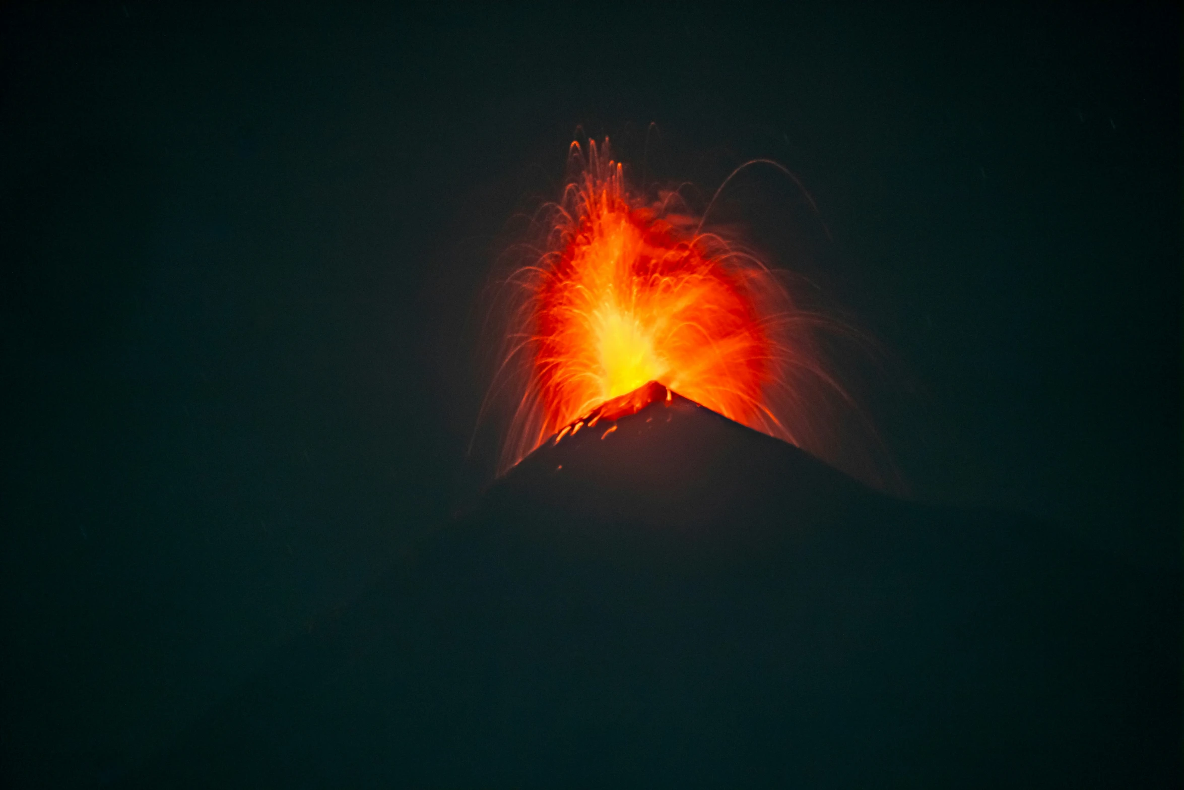 bright lava flows from the top of a mountain