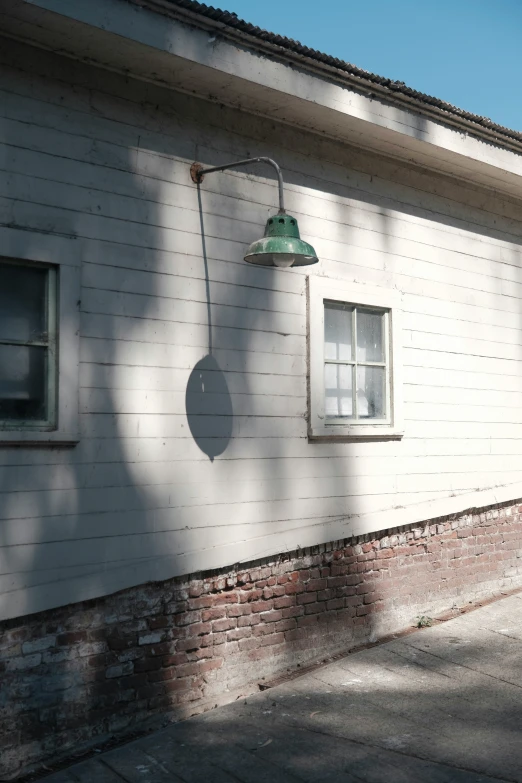 a white house with an open window and an old green street light on the side