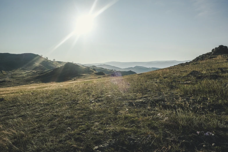 the sun shines brightly over a hilly area