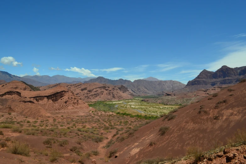 an arid desert valley with green fields and mountains in the background