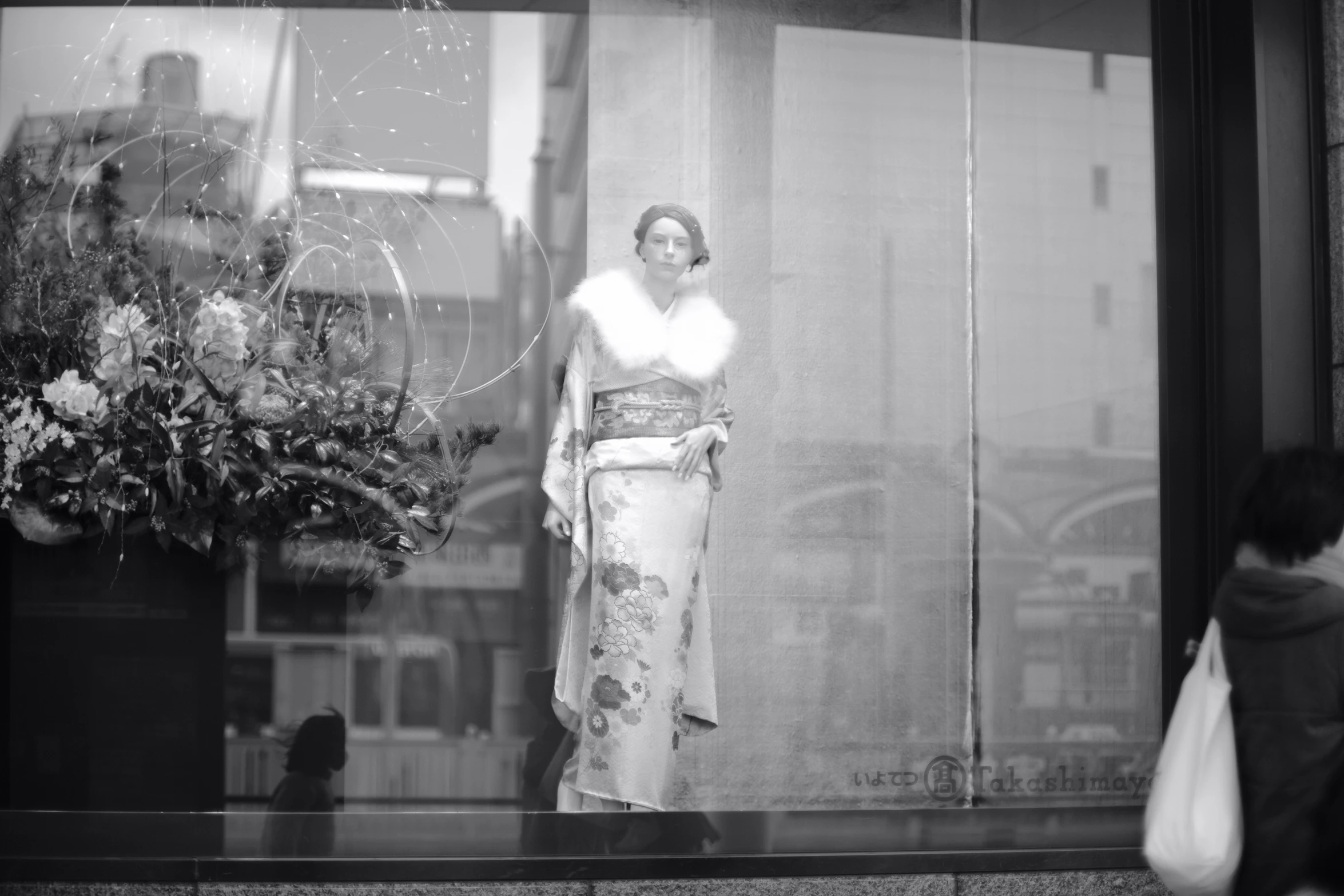 a woman stands behind the display glass of a store window