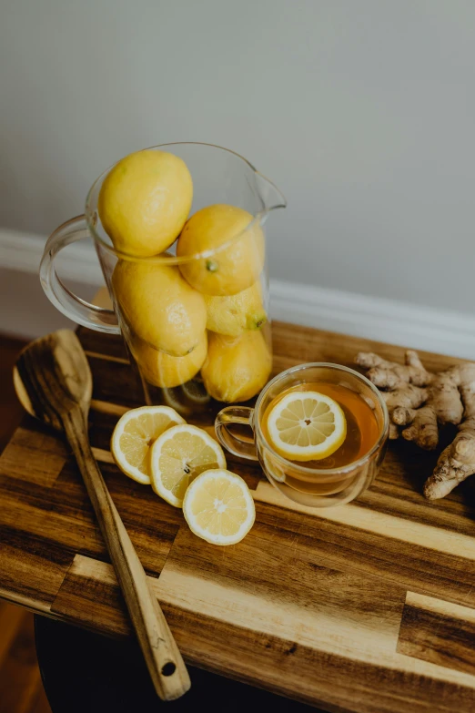 the pitcher of tea and a mug have lemons and ginger