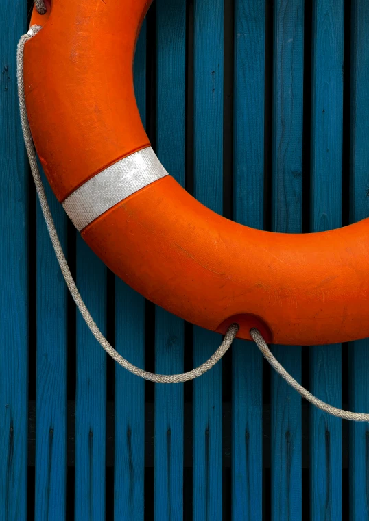 a life preserver with rope and white handles on a blue wooden background