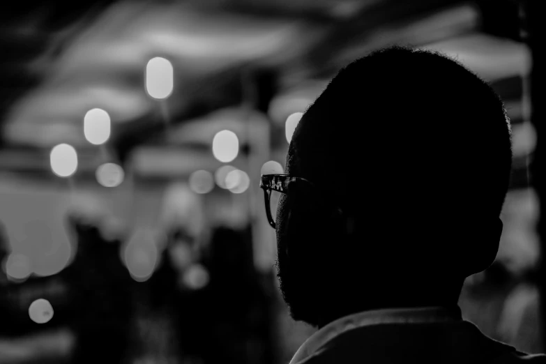 the silhouette of a man with glasses standing in front of some lights