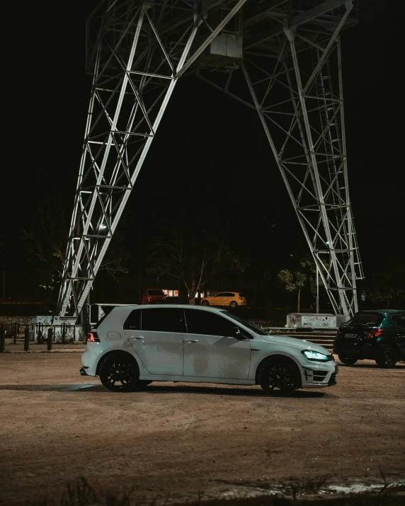 a grey car driving in front of a metal structure