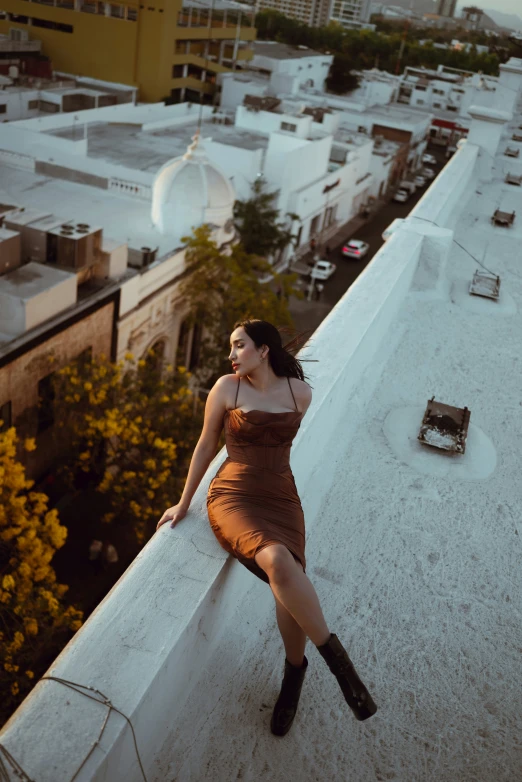 a woman in a brown dress posing on a wall