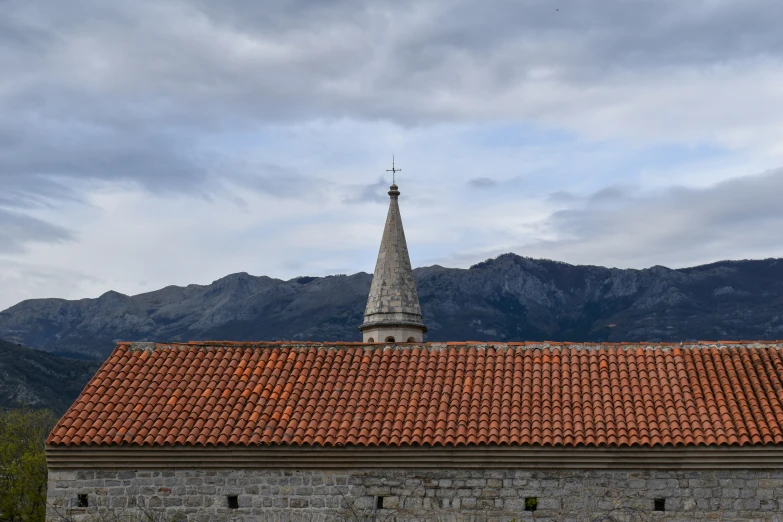 an old building with red tile on the roof and steeple