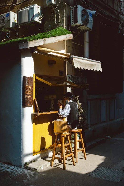 a man sits at a wooden counter with plants on top