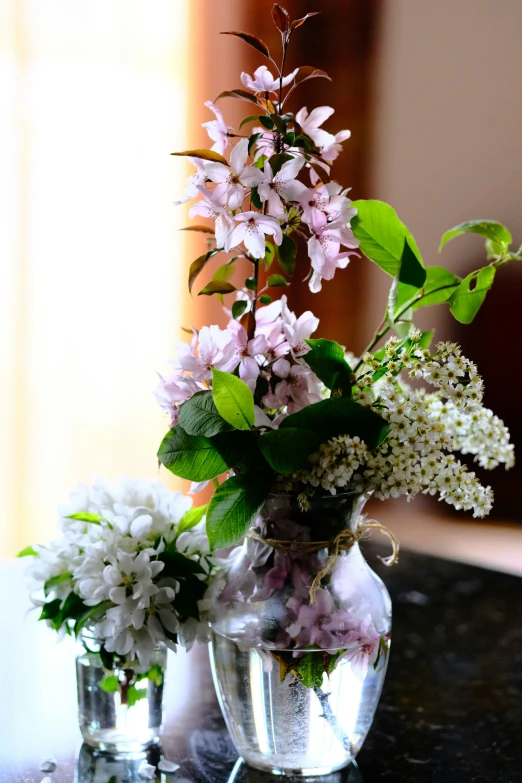 an arrangement of flowers in clear vases are on a table