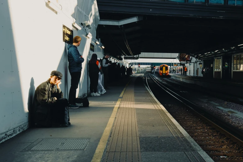 a woman waits at a train station with her luggage