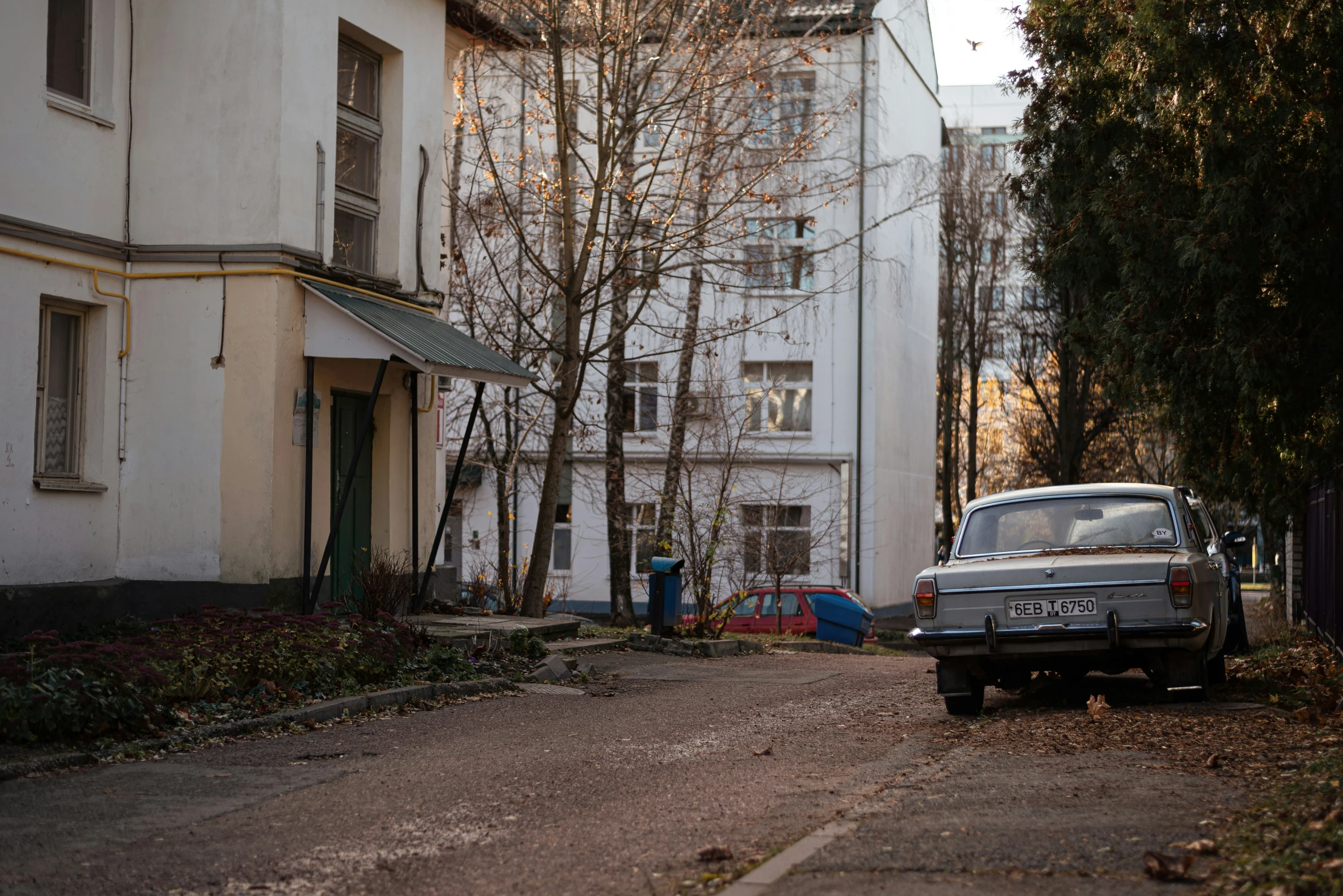 old car parked on the street next to a big house