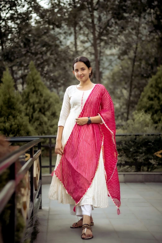 a woman in a pink and white outfit standing on a bridge