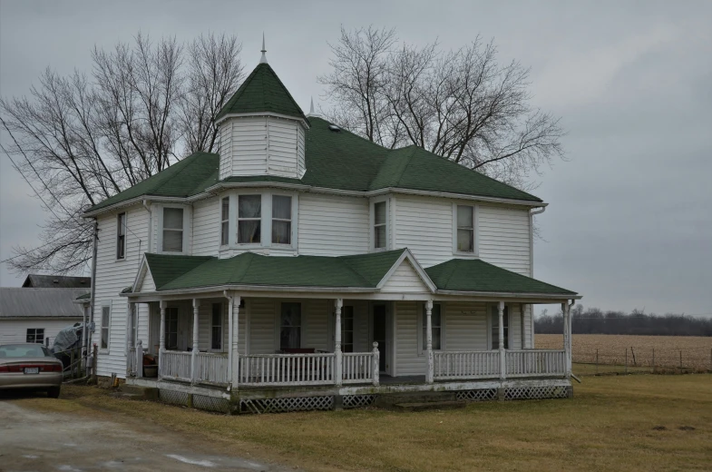 a white two story house with green roof