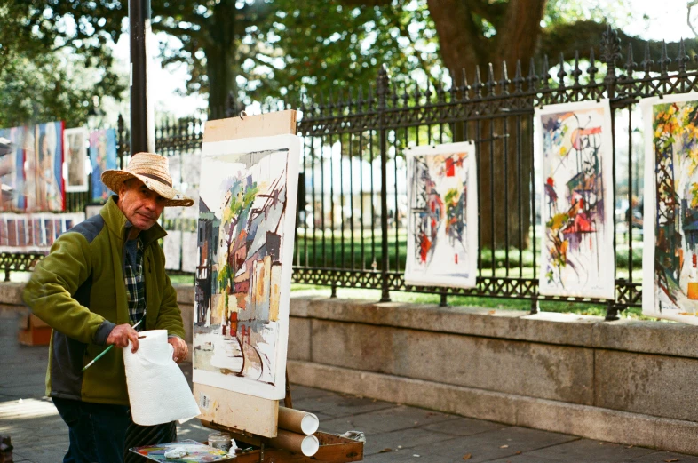 a man standing in front of a table covered in paintings