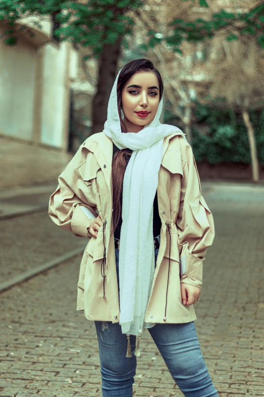 woman in trench coat and scarf standing on a brick street