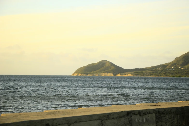 the ocean in front of two small mountains is empty