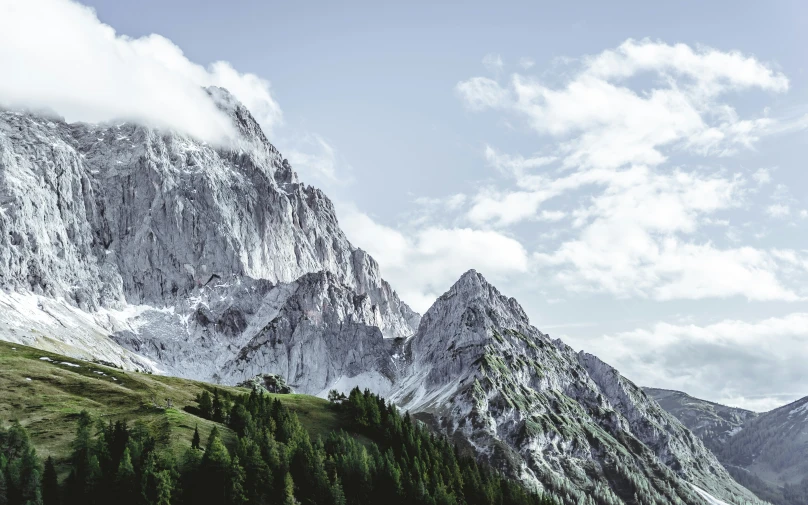 a lone person stands in a grassy field next to mountains