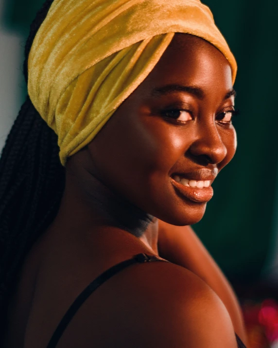 a woman in a yellow towel smiles at the camera