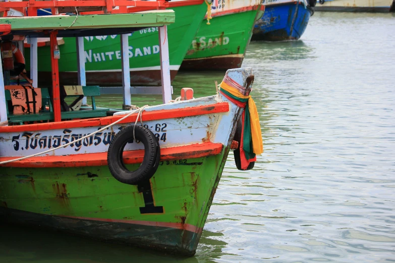 a colorful boat floating in the water with rope hanging from it's front end