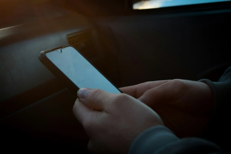 the woman is holding her phone while she drives