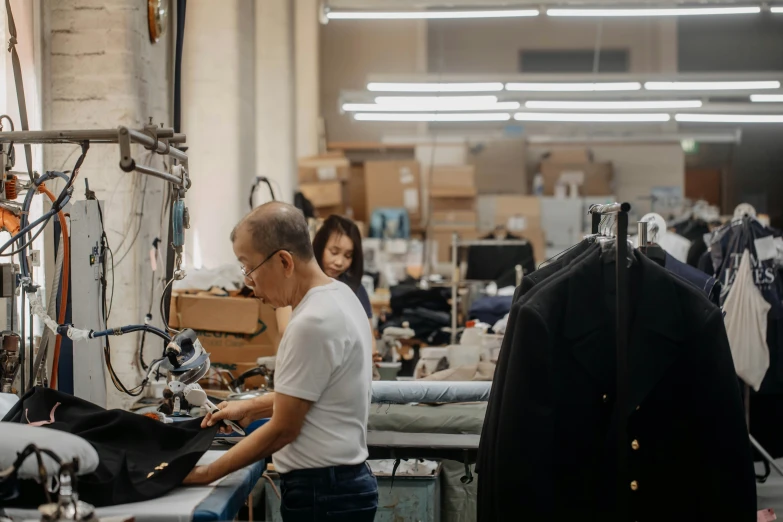 two people in a shop working on clothing