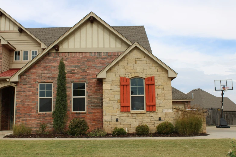 a two story brick house with red shutters