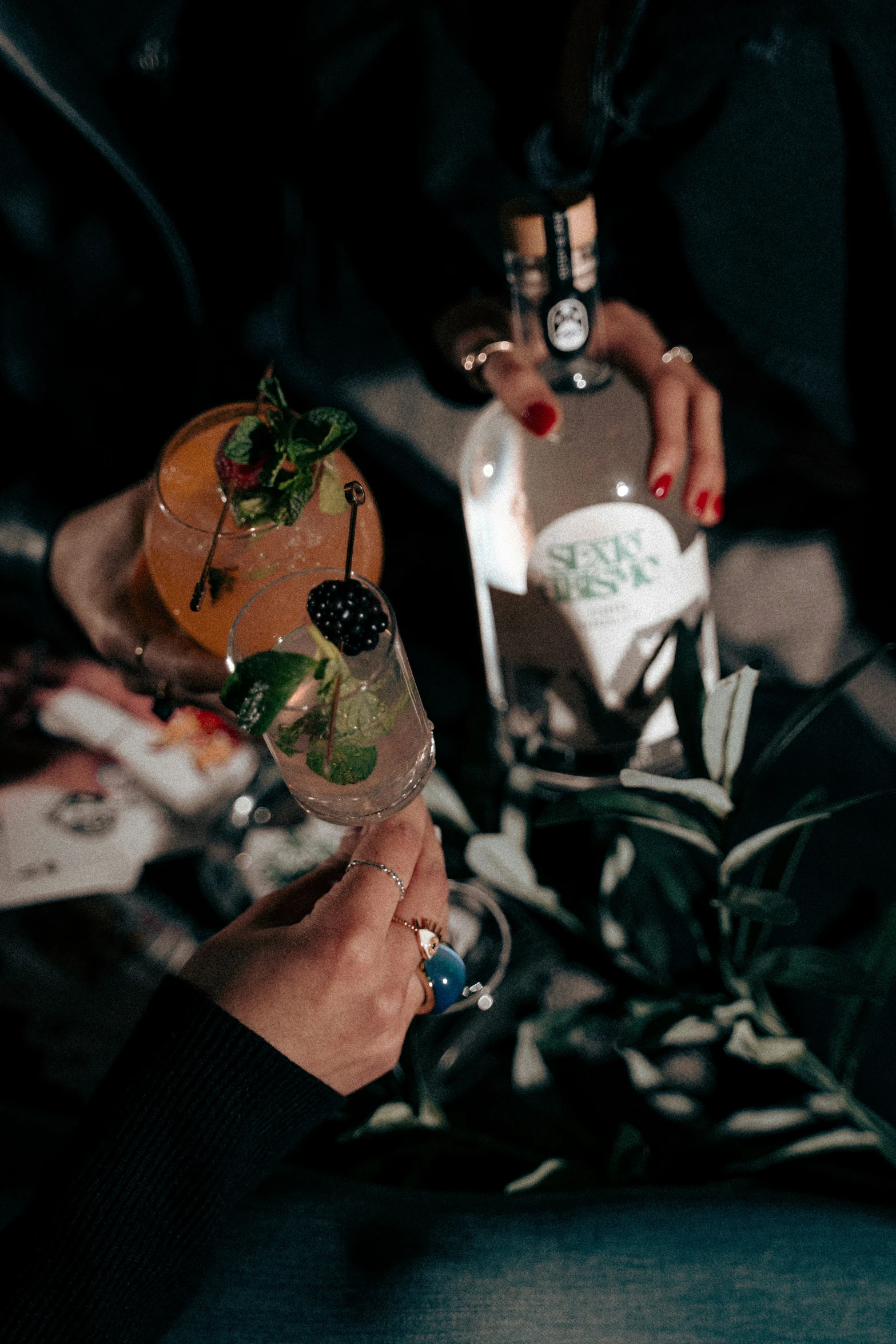 a woman with black nails holding two drinks