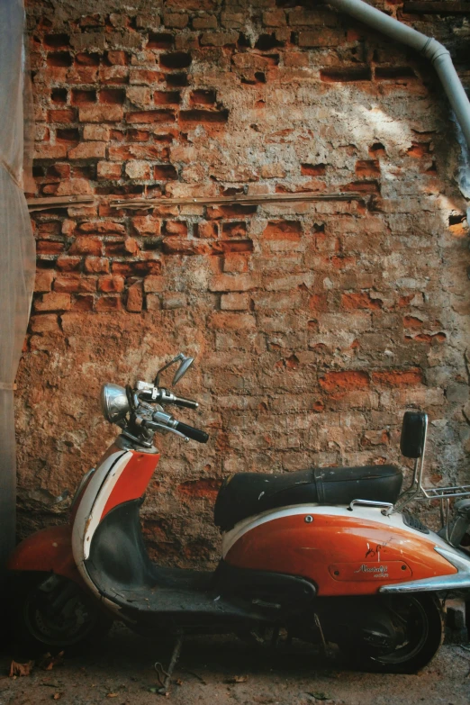 an old motorcycle is parked in front of a brick wall