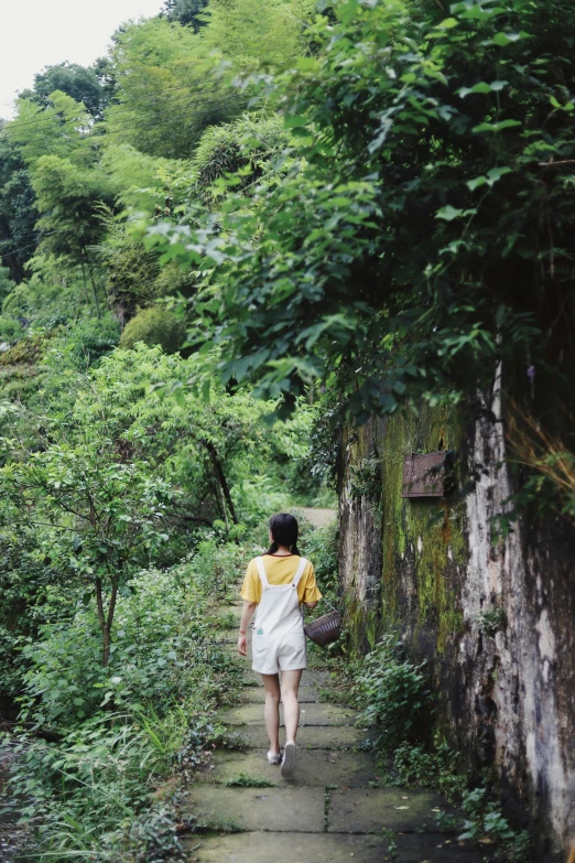 a woman is walking in a path in the woods