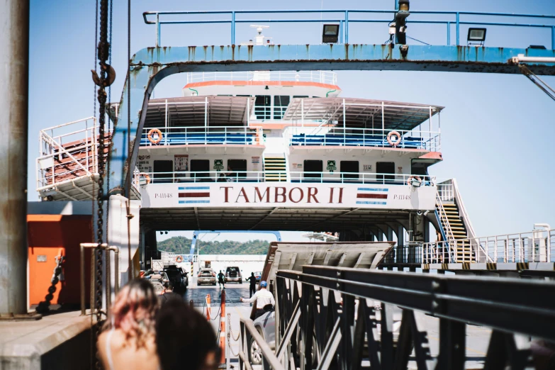 people walking up to a ship under a bridge