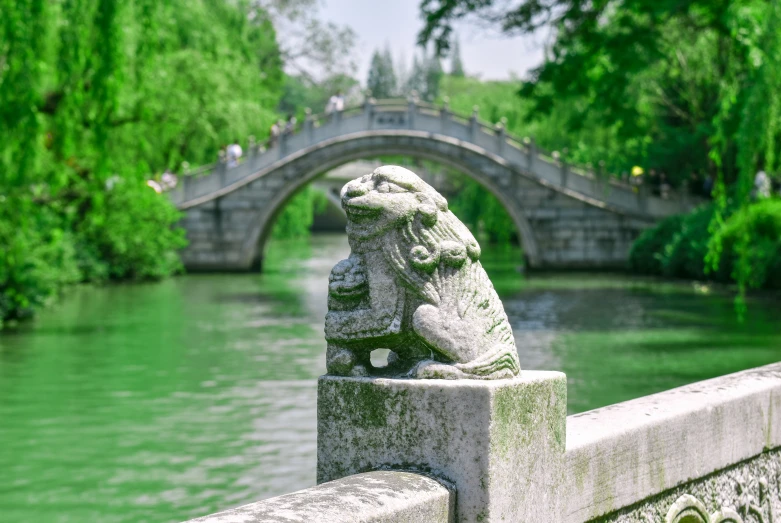 an animal statue is sitting on a stone ledge near the water