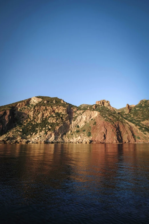 a rock hill next to the ocean on a clear day