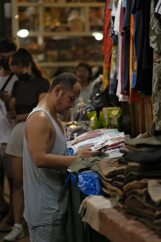 a man looks at items for sale on a market stall