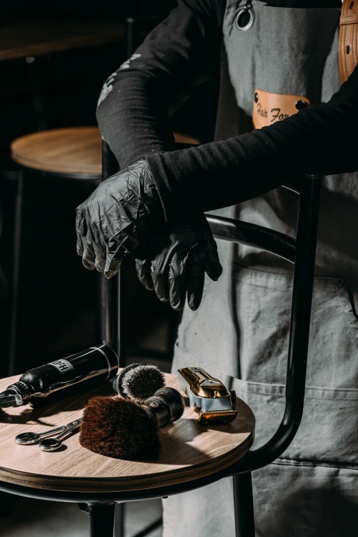 the person in gloves and latex gloves are standing next to a small table with tools on it