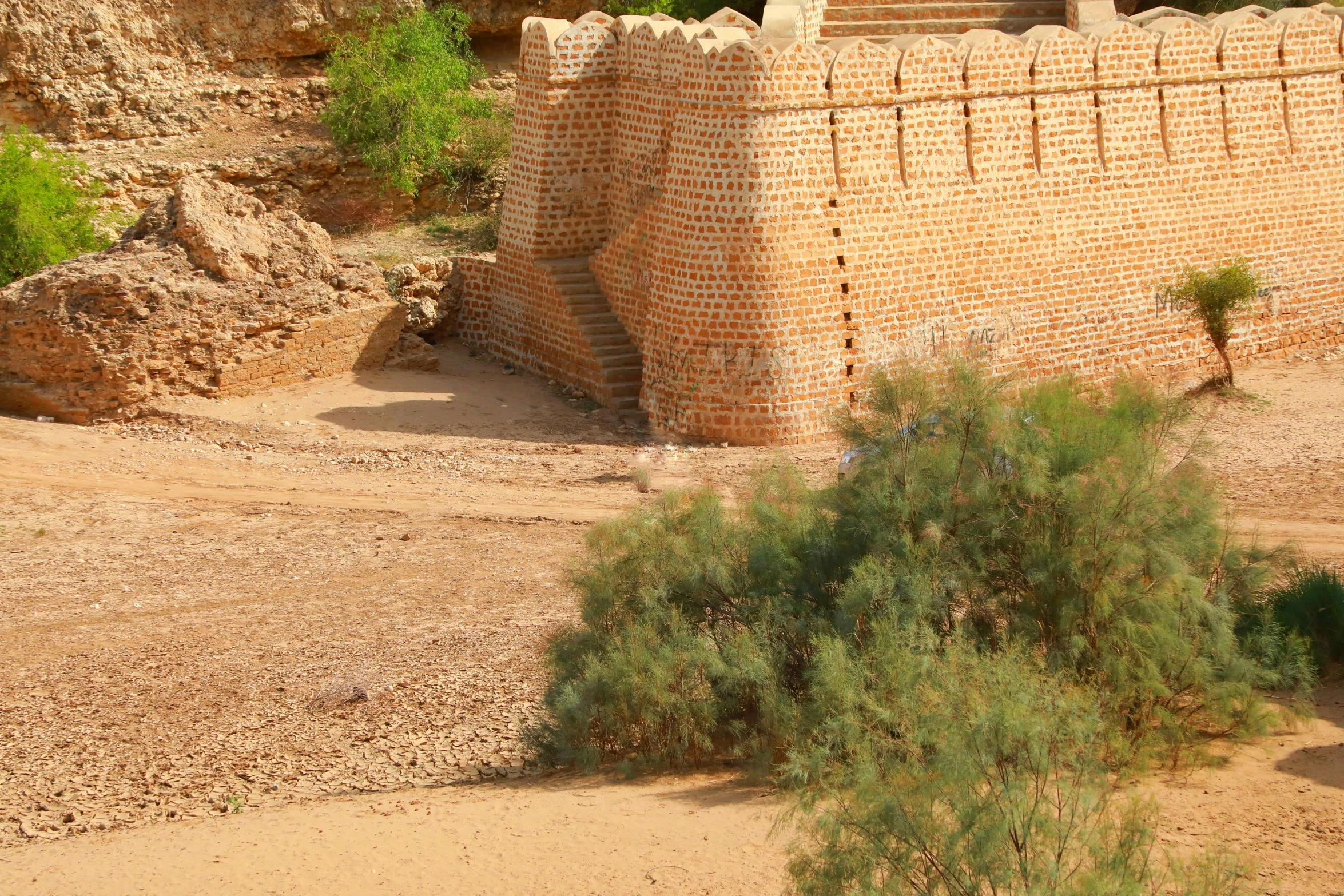 a brick tower surrounded by dirt and greenery