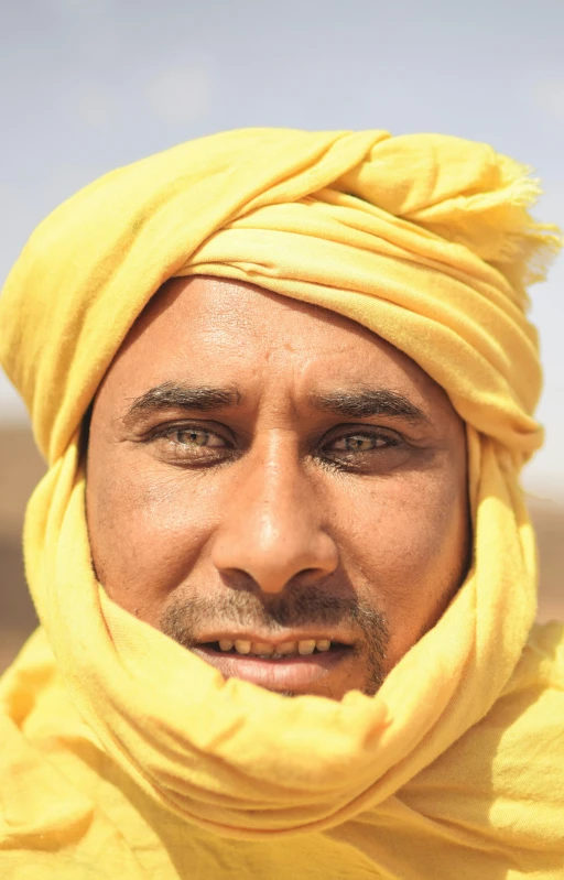 a man in a yellow turban looks into the distance