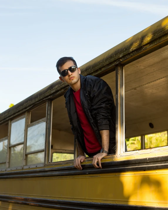 man wearing sunglasses standing on the edge of an abandoned school bus