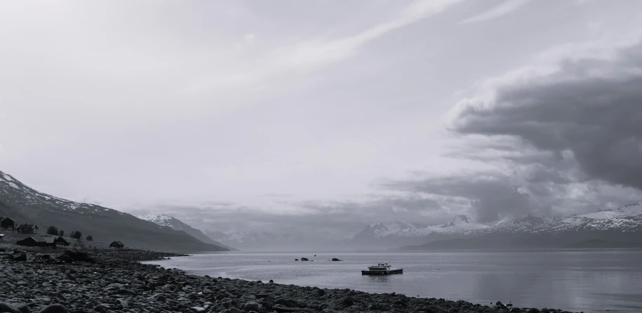 a boat out on the ocean under some dark cloudy skies