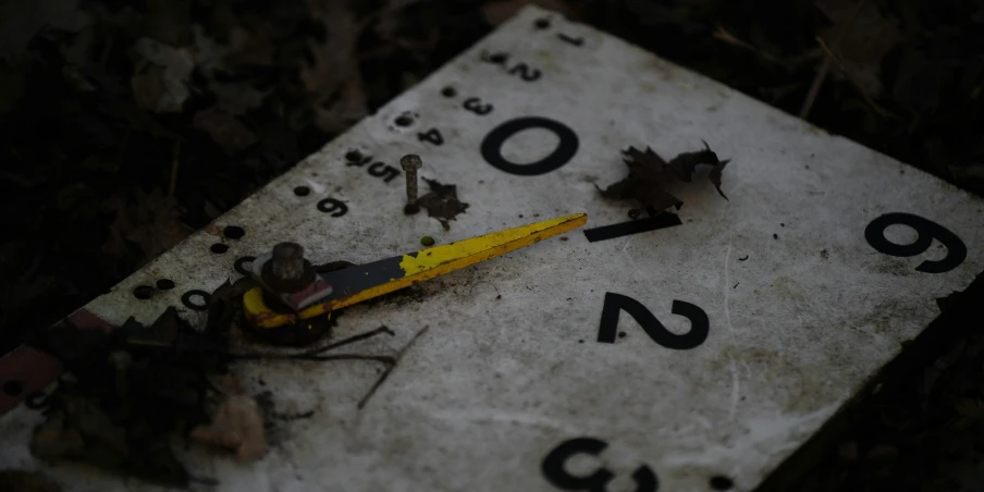a yellow pencil resting on top of a white sign with numbers