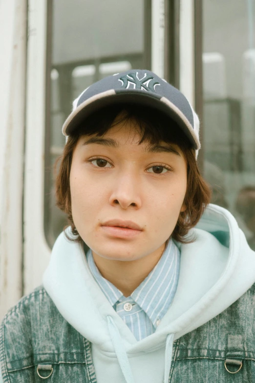 a girl standing in front of a building wearing a baseball cap