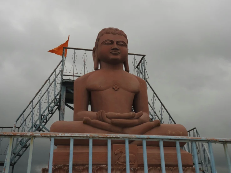 a buddha statue in a fenced area with a staircase behind it