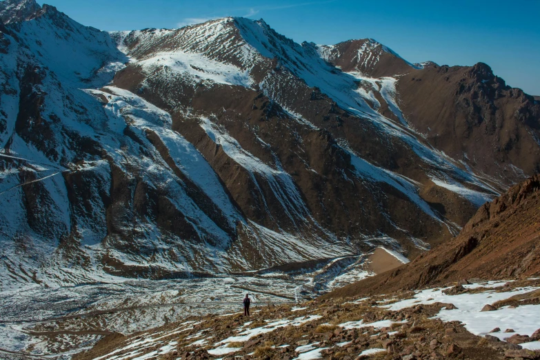 a person standing on the side of a mountain with a snow covered top