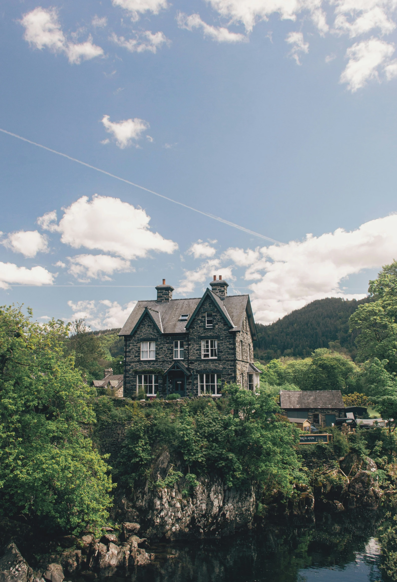 a stone house in the middle of a field and a river